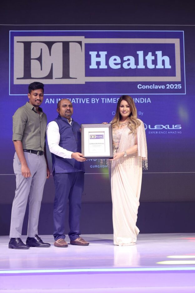 Three individuals on stage at the ET Health Conclave 2025 award ceremony, with one holding a framed award. The backdrop features the event logo, "ET Health" and "Conclave 2025," along with the Lexus sponsorship branding. The scene is illuminated with purple and blue lighting.